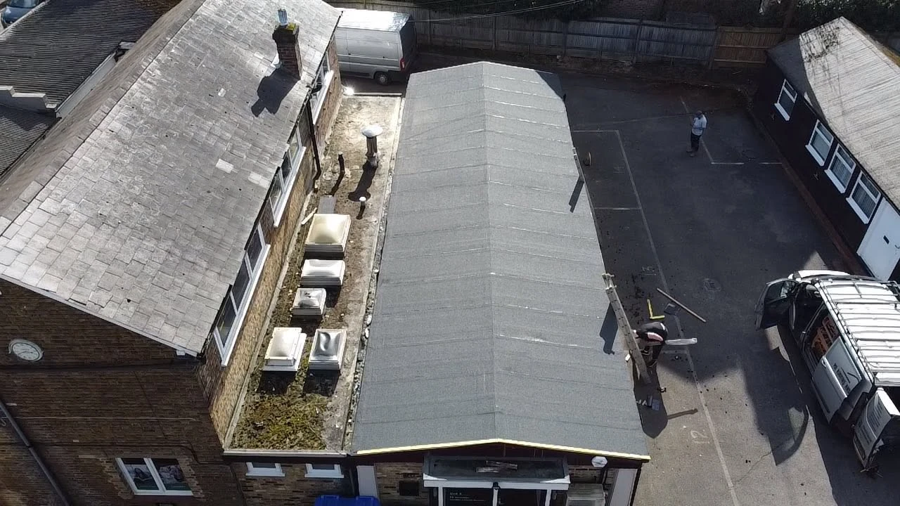 Aerial view of a rooftop, a van, and two people near a building in a parking area.